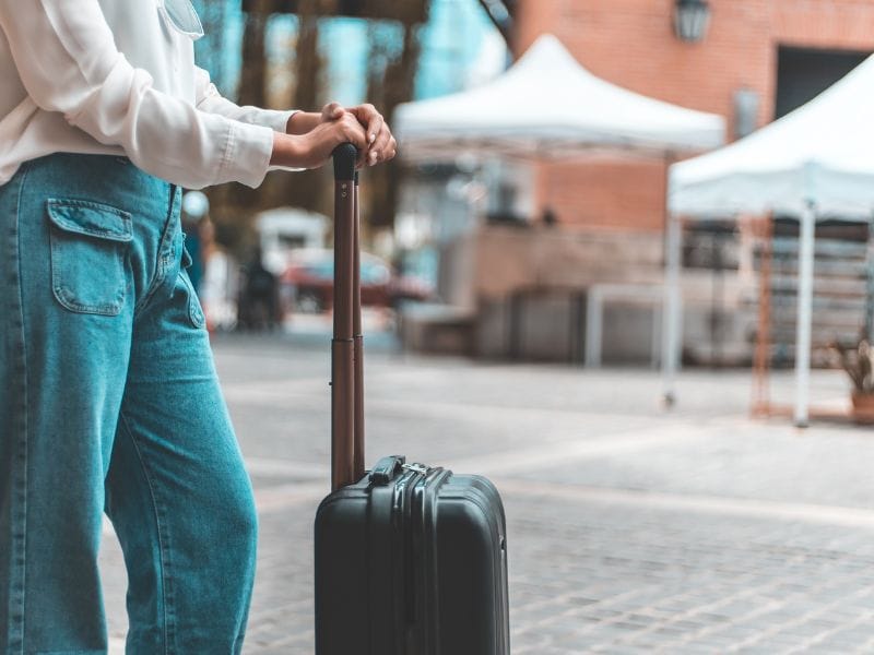 ragazza con valigia in una piazza