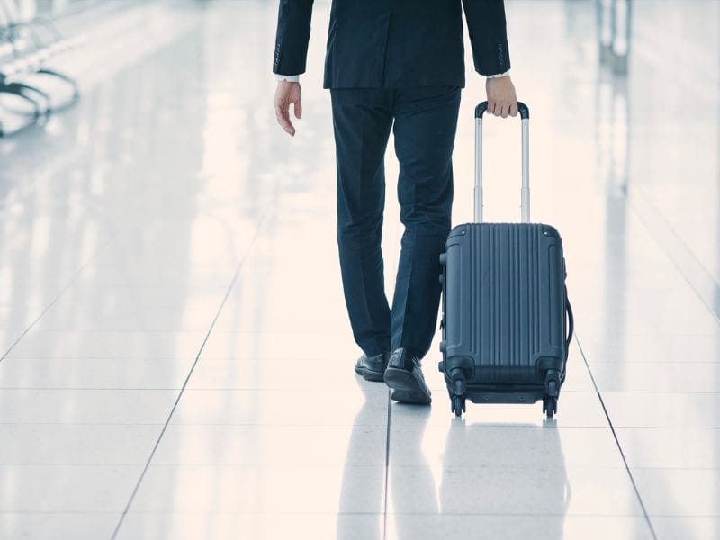 uomo d'affari trascina il trolley in aeroporto