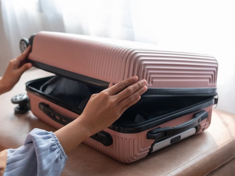 ragazza chiude una valigia rosa