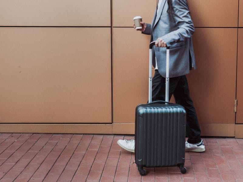 uomo che fa turismo business con valigia e caffè